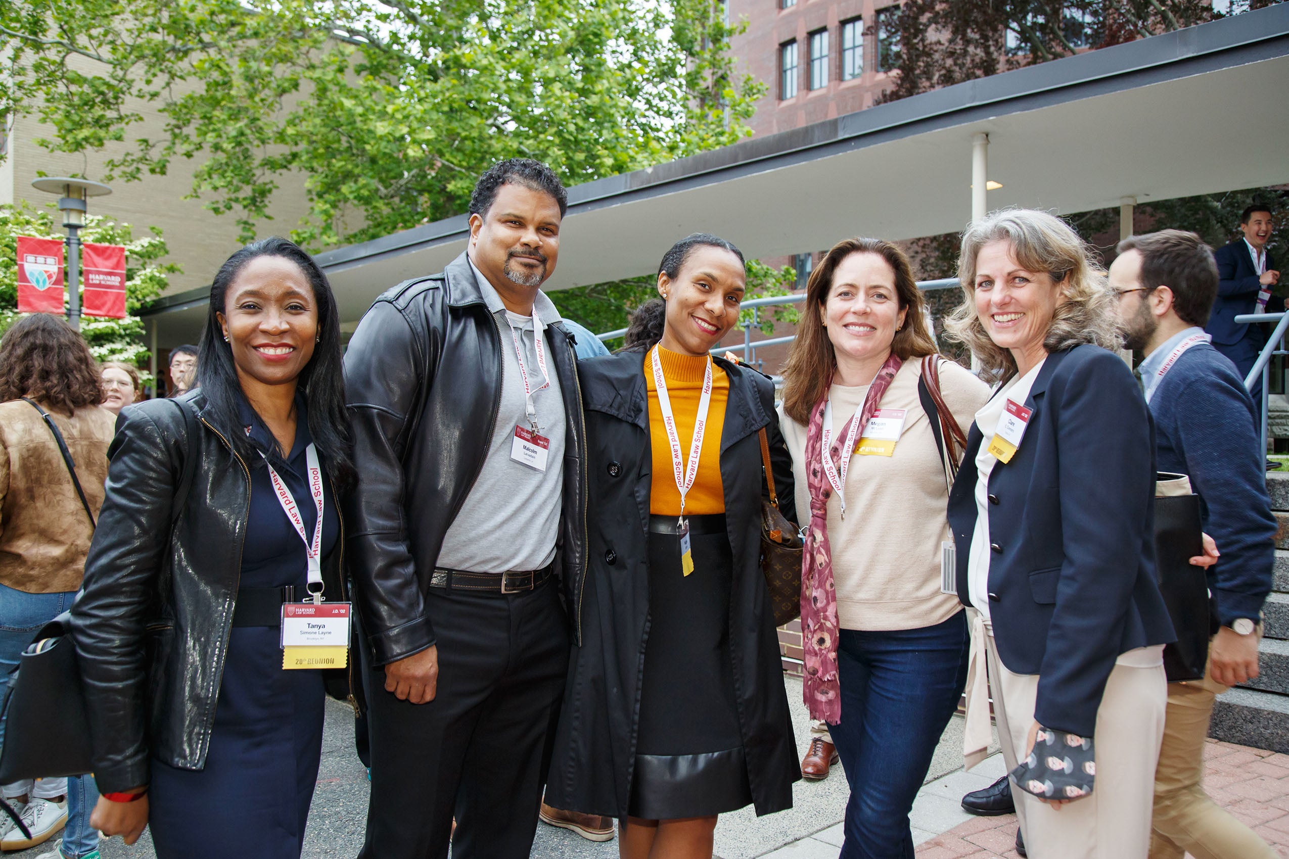 Five people wearing nametags, smiling outside.