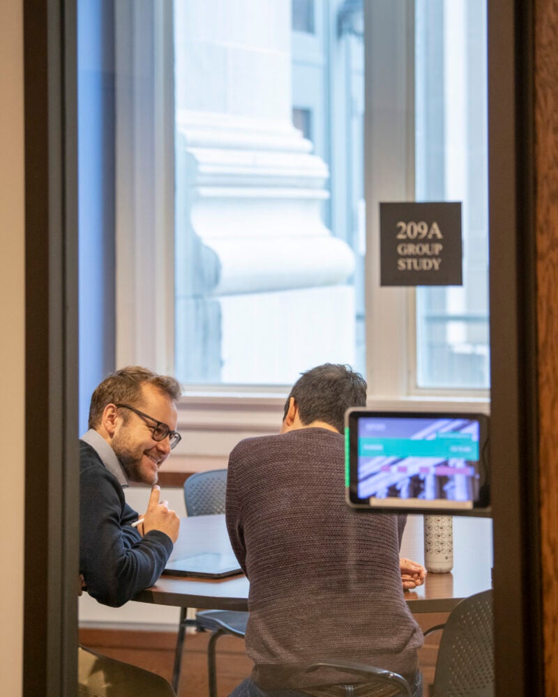 2 students sit in a private room and have a conversation