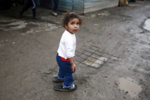 A Roma girl plays in the mud in the Cesmin Lug refugee camp.
