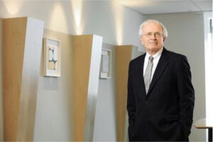 A man standing to the right of a wall with modern artwork