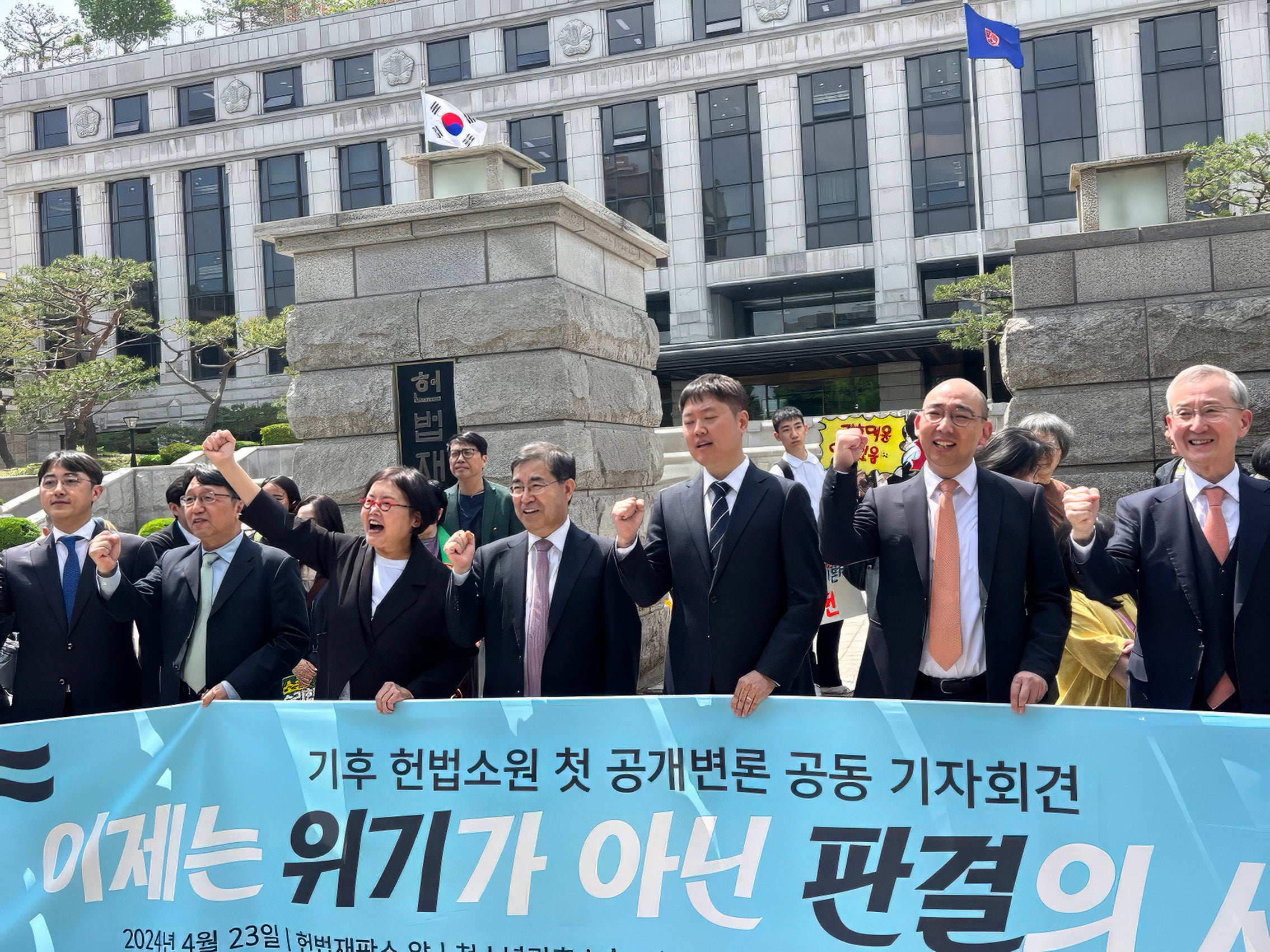 The litigation team lines up behind a sign in outside front of the South Korean Constitutional Court.